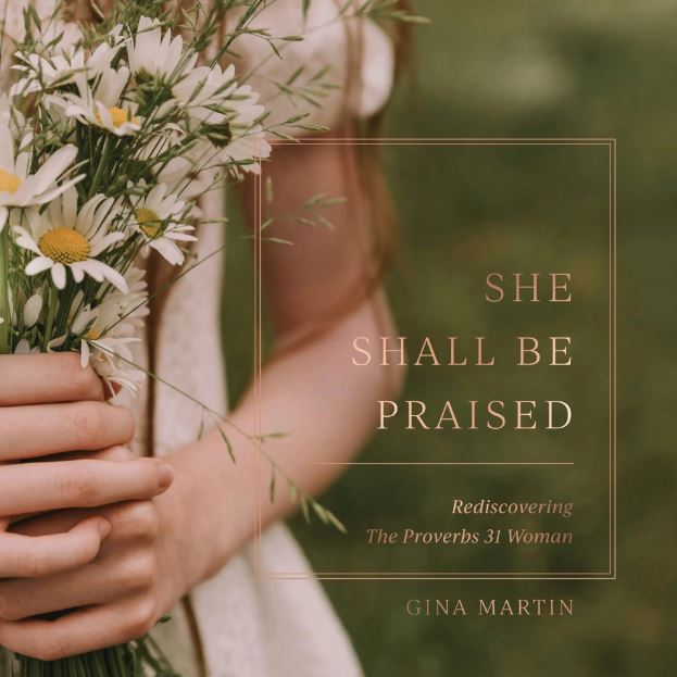 Person holding a bouquet of flowers with text overlay 'She Shall Be Praised' by Gina Martin.