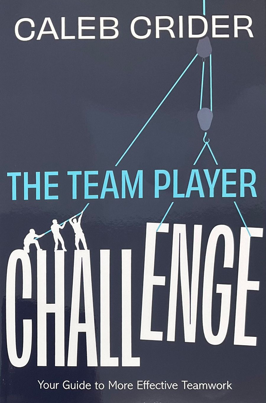 Book cover for 'The Team Player Challenge' by Caleb Crider, featuring a dark slate-blue background with white and light blue text and a pulley graphic.